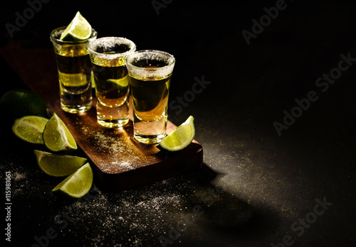 Mexican Gold Tequila with lime and salt on wooden table, selective focus. Copyspace.