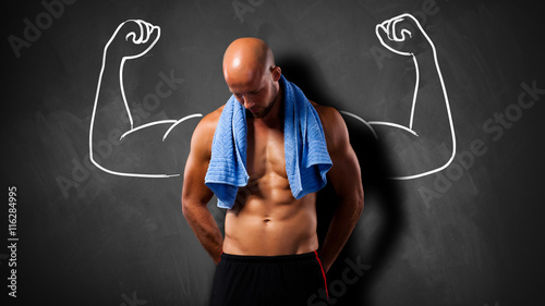 Muskulöser Mann vor einer Kreidetafel mit Kraftgeste