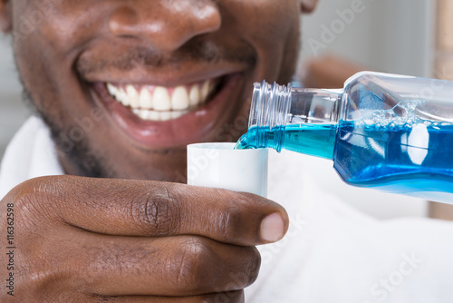 Close-up Of A Man Pouring Mouthwash Into Cap