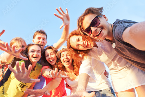 Group of happy young friends doing selfie against the blue sky.