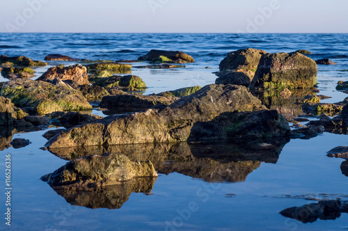 Reflection of rocks in the sea calm seaweed 