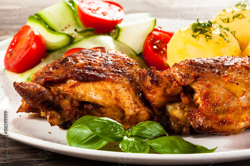 Barbecued chicken legs with boiled potatoes and vegetables 