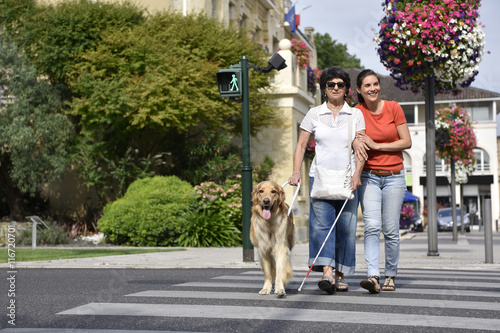 Senior blind woman crossing the street with assistance