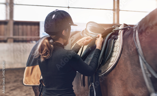 Jeździec kobieta dostosowuje jej strzemiona na siodle