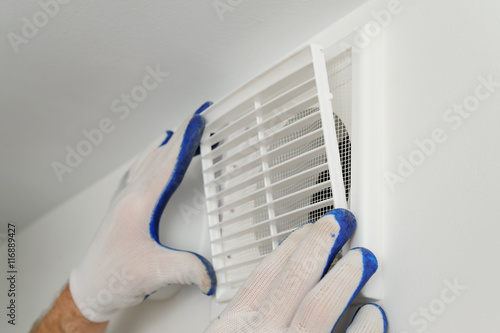 Worker installs ventilation grille.