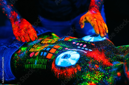 Concept. DJ playing at the club. Girl painted in UV powder as a