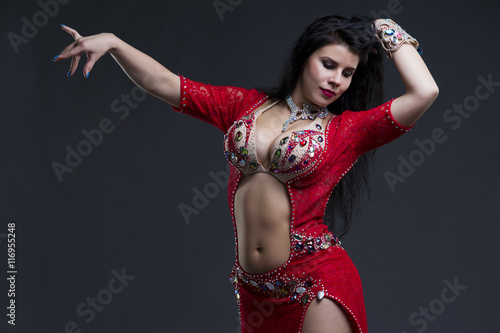 Young beautiful exotic eastern women in ethnic red dress on gray background