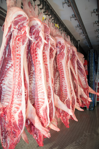 Schlachtung - Schweinehälften hängen am Haken