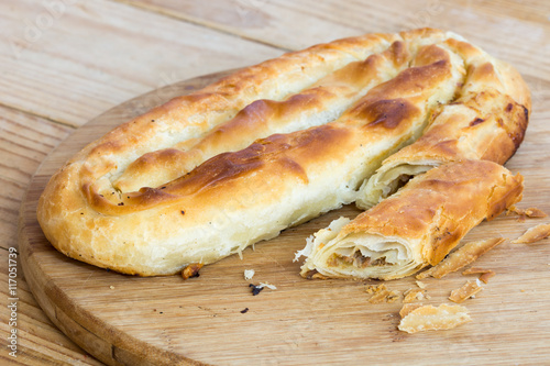 Sliced burek with meat on the wooden board. Rustic food.