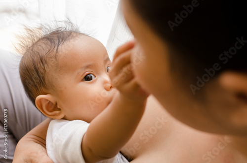 Mother breastfeeding her newborn baby beside window