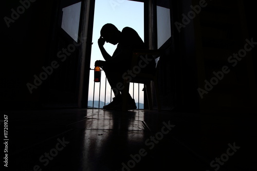 An alcoholic man with a bottle in his hand against the front window