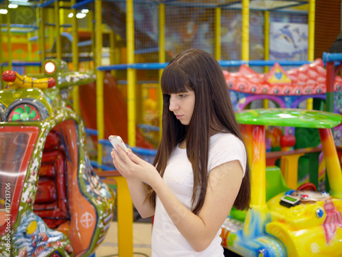 Young woman playing Pokemon GO indoor at shopping center, using smart phone. Girl play the popular smartphone game - catching pokemon in hypermarket mall