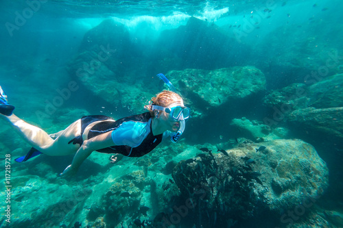 Young lady snorkeling over coral reefs in a tropical sea. Similan Islands in Thailand, one of the tourist attraction of the Andaman Sea.