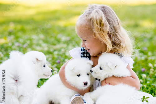 happy little girl playing with Samoyed puppy