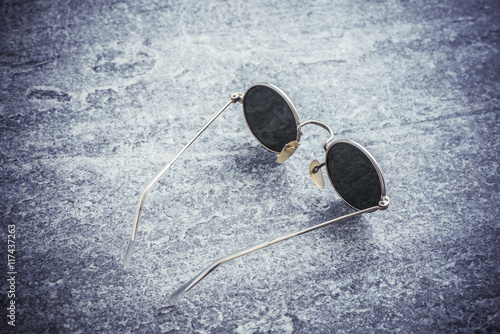 Round sunglasses on stone table, Retro eyewear. Still life of cool design accessory.