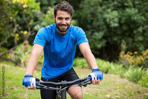 Male athletic standing with mountain bike in forest