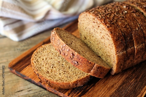 Sliced whole grain bread with nutritious flax seeds on wooden board