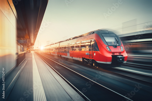 Piękna stacja kolejowa z nowoczesną czerwoną kolejką przy słońcach