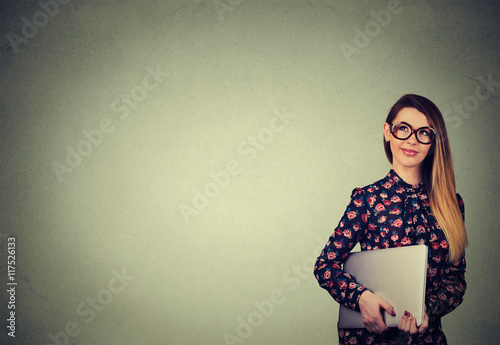 Beautiful happy woman standing with laptop over gray wall background
