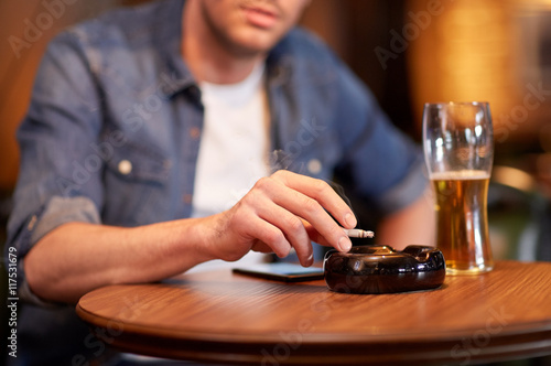 man drinking beer and smoking cigarette at bar