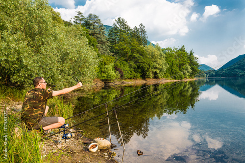 Fishing adventures. Fisherman while groundbait with boilies, using a slingshot fishing 