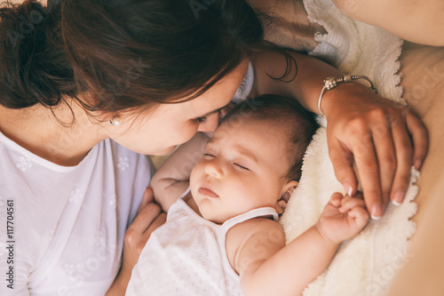 Beautiful young mom near sleeping 3 months baby.