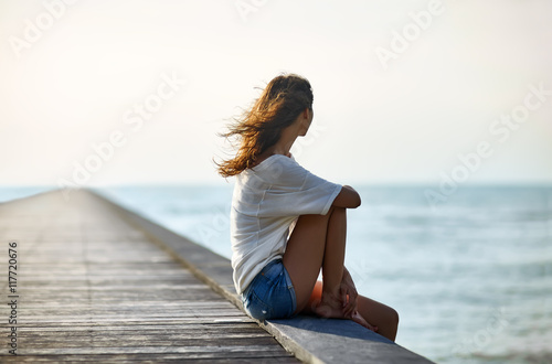 Young beautiful woman sitting on the pier