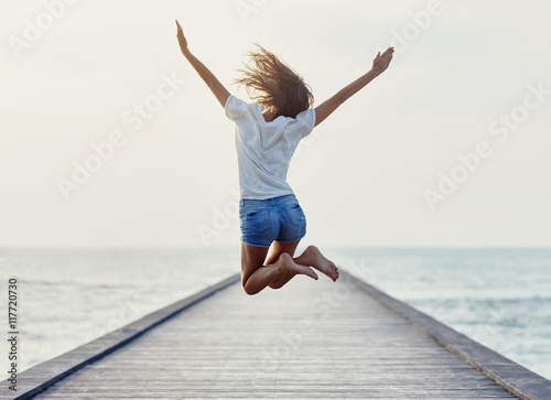 Back view of jumping girl on the pier