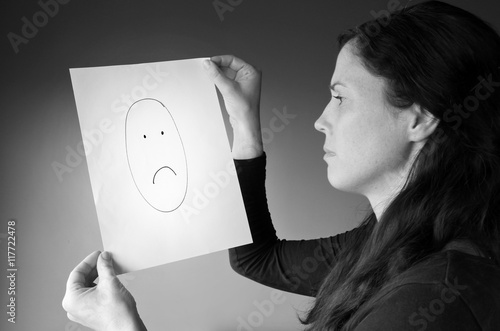 Young woman looks at a drawing with a sad face