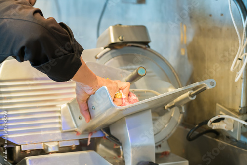 Chef operating meat slicer machine 