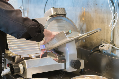 Chef operating meat slicer machine 