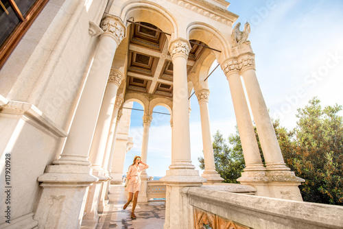 Happy woman running on the castle terrace near the sea. General plan with columns and arches