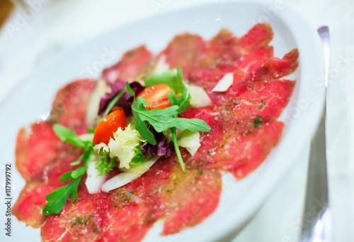 Thin slices of meat carpaccio in white plate