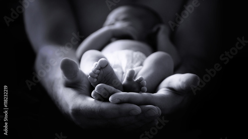 male hands holding a newborn baby