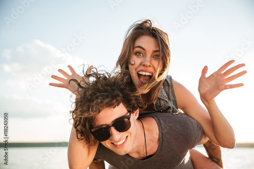 Young happy smiling couple in love piggyback at the beach