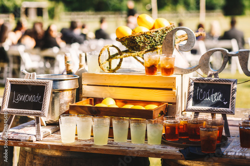 Glasses with lemonade and iced tea stand on wooden board outside