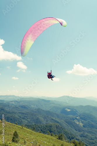 Tandem paragliding flight with hills and blue sky