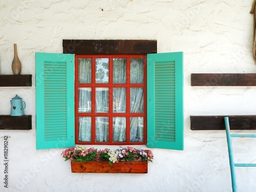 Window box on the white wall with colorful geranium