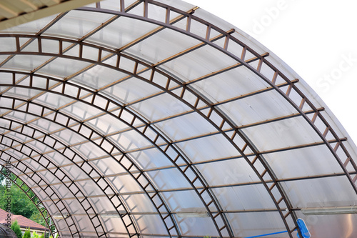 A canopy made of polycarbonate arc against the blue sky. Metal construction. 