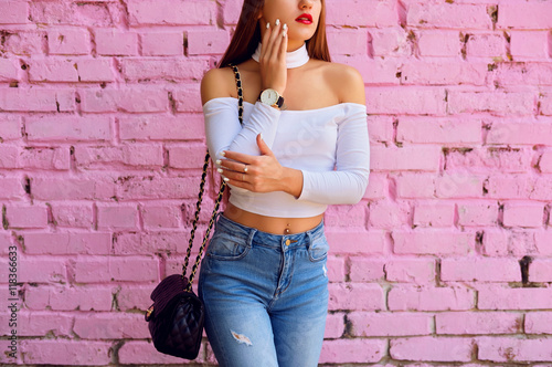 Fashion young woman with black bag posing near pink wall