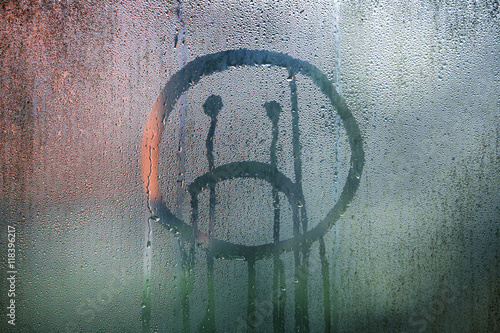 Sad upside down smiley hand drawn symbol on wet glass background.