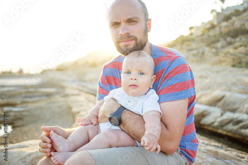 Father and his son have fun at the sea beach at the sunset