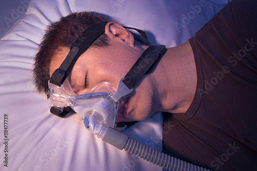 Middle age asian man with sleep apnea sleeping using CPAP machin