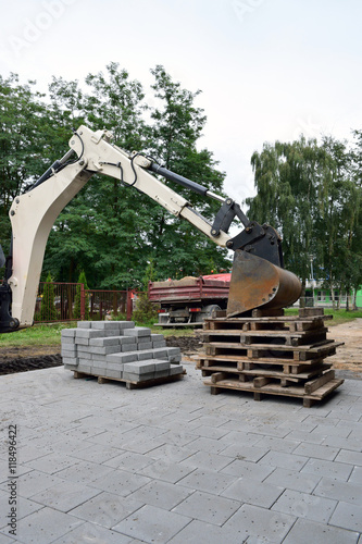 Elementy potrzebne podczas budowy chodnika: koparka, płyty chodnikowe, ciężarówka, żwir