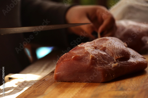 świeże mięso na drewnianej desce do krojenia i ręka z nożem