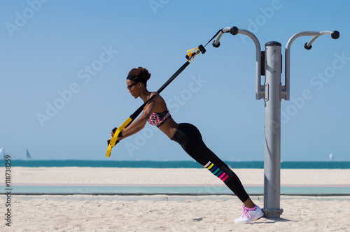 Female african with slim and lean body doing exercises using special ropes for intense body training. Outdoor activities