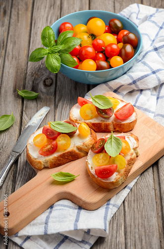 Bruschetta with feta cheese and cherry tomatoes on wooden background, selective focus
