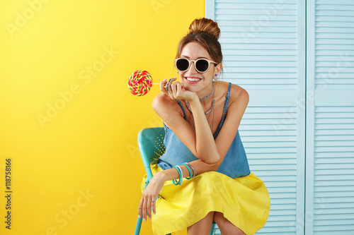 Beautiful girl with candy on color background