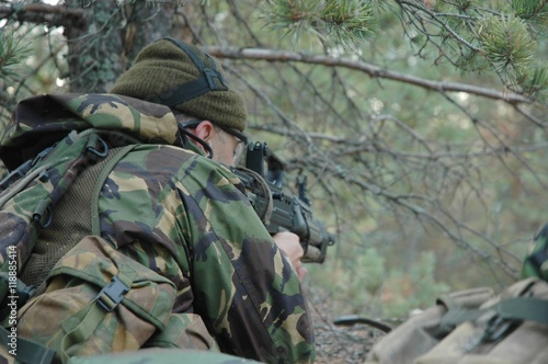 Боец в лесу в засаде целиться во врага.