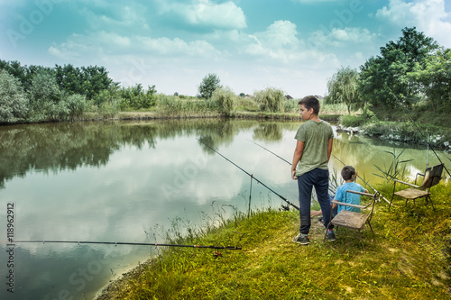 Father and sons fishing on river